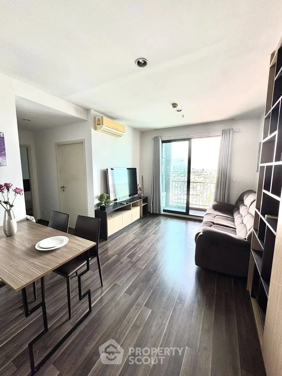 Modern living room with sleek furniture and large window offering city view