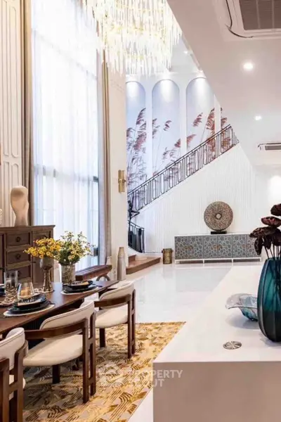 Luxurious modern living room with high ceilings, elegant chandelier, and stylish decor.