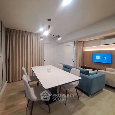 Modern living room with stylish dining area and cozy seating, featuring elegant lighting and contemporary decor.
