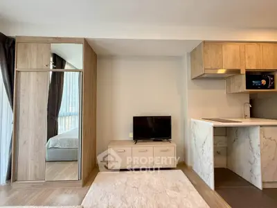 Modern studio apartment with open kitchen and cozy living area, featuring sleek cabinetry and natural light.
