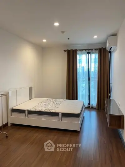 Spacious bedroom with modern furnishings and large window for natural light.
