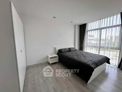 Spacious modern bedroom with large window and sleek furnishings
