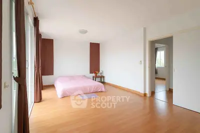Spacious minimalist bedroom with wooden flooring and natural light