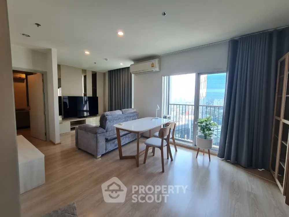 Modern living room with large window and stylish furniture in a high-rise apartment.