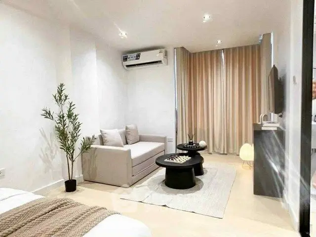 Modern living room with sleek furniture and neutral tones, featuring a cozy sofa and stylish decor.