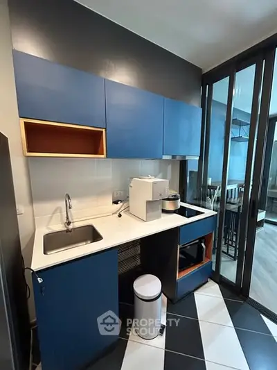 Modern kitchen with sleek blue cabinets and stylish black and white flooring.