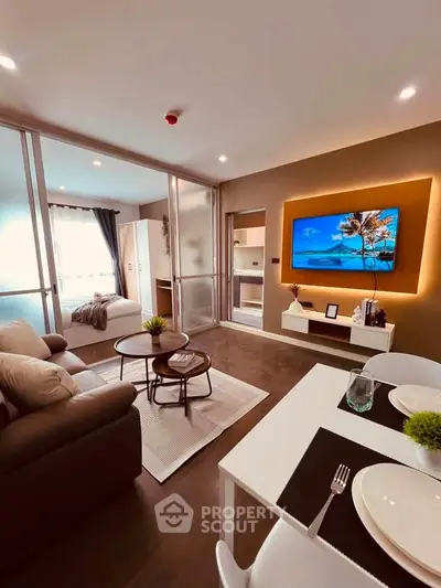 Modern open-plan living room with stylish decor and natural light, featuring a cozy seating area and a sleek TV setup.