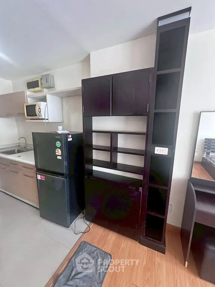 Modern kitchen with sleek black fridge and microwave, featuring ample storage and contemporary design.