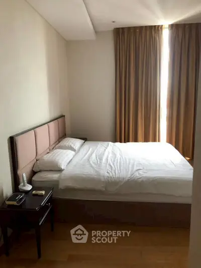 Cozy bedroom with natural light and elegant curtains in modern apartment.