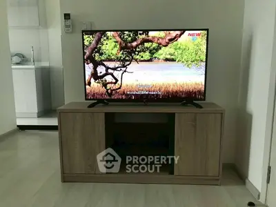 Modern living room with sleek TV stand and flat-screen TV, adjacent to a minimalist kitchen.