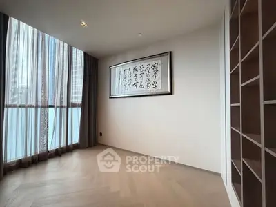 Spacious room with elegant wooden flooring and large window, perfect for a serene living space.