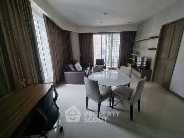 Spacious living room with modern furniture and large windows in a high-rise apartment.