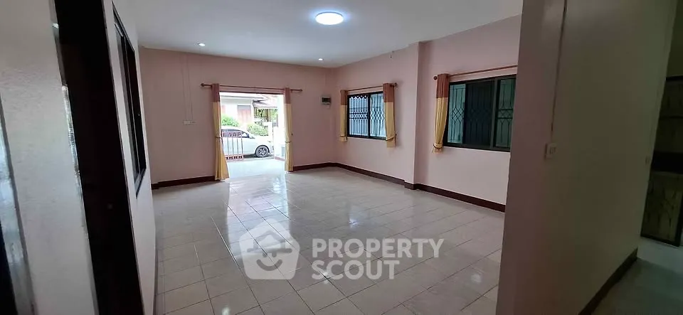 Spacious empty living room with tiled floor and large windows in a residential property.