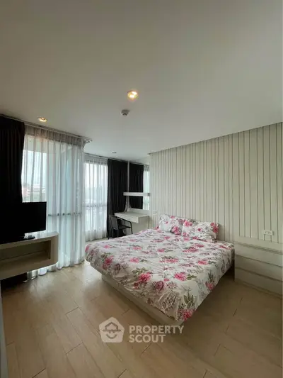 Spacious bedroom with floral bedding and natural light in modern apartment