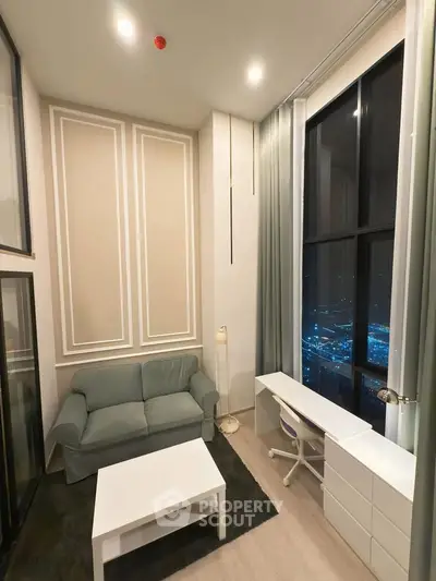 Modern living room with high ceilings and city view, featuring a cozy sofa and sleek desk setup.