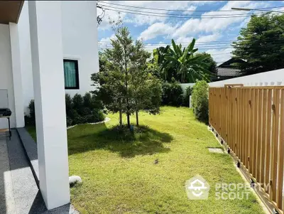 Charming garden view with lush greenery and modern fence in a serene residential setting.