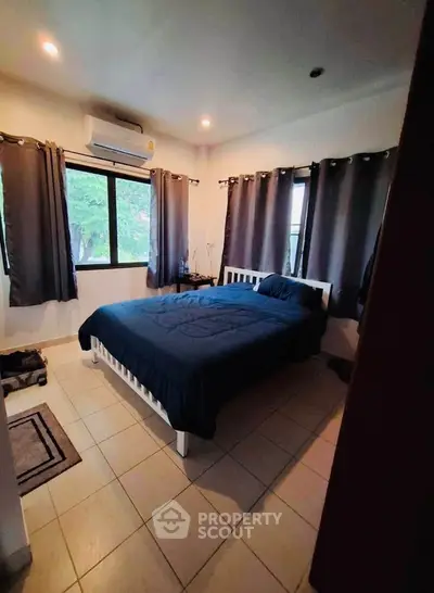 Cozy bedroom with large windows and modern decor, perfect for relaxation and comfort.
