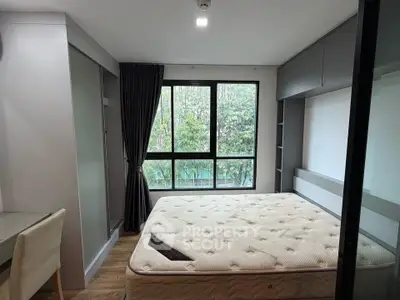 Modern bedroom with large window and forest view, featuring a comfortable mattress and sleek storage solutions.