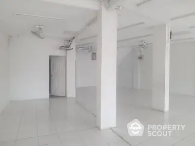 Spacious white tiled commercial space with ceiling fans and ample natural light.