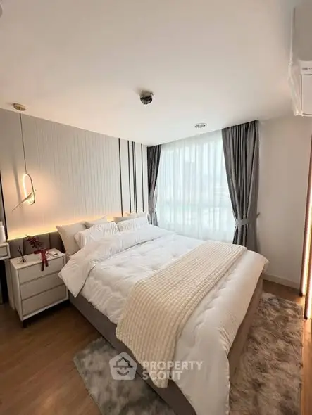 Elegant bedroom with cozy bedding and modern lighting in a stylish apartment.