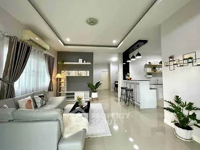 Modern living room with open kitchen, sleek decor, and natural light.