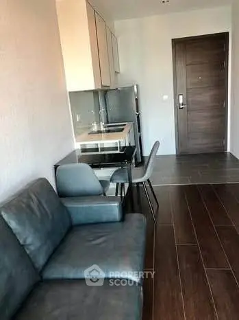 Modern compact living room with sleek kitchen and dining area, featuring stylish furniture and wooden flooring.