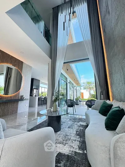 Luxurious modern living room with high ceilings and large windows, featuring elegant decor and spacious layout.