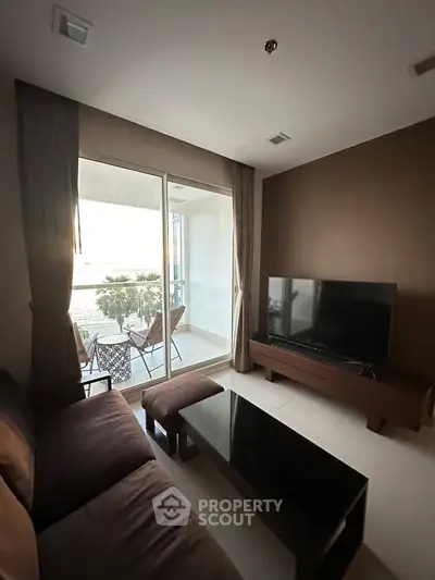 Modern living room with balcony view, featuring sleek furniture and natural light.