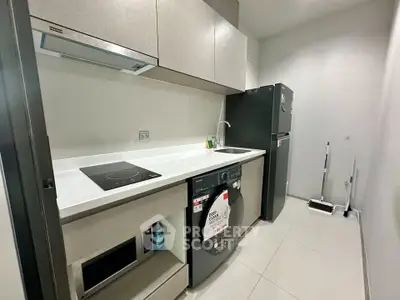 Modern kitchen with sleek appliances and minimalist design, featuring a washing machine and induction cooktop.
