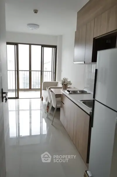 Modern kitchen with open layout and dining area in a bright apartment with balcony view.
