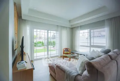 Spacious living room with large windows and garden view, featuring cozy seating and modern decor.
