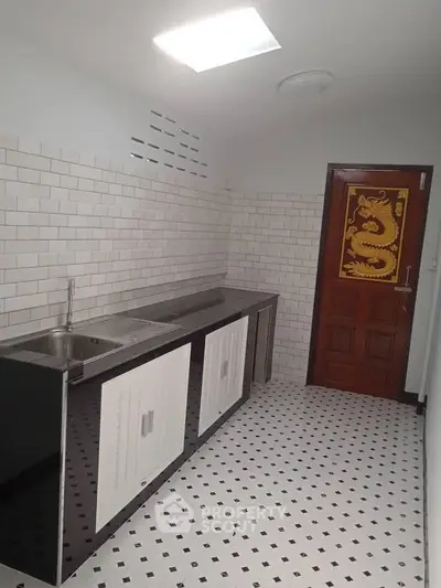 Modern kitchen with sleek design and dragon-themed door, featuring white subway tiles and checkered flooring.