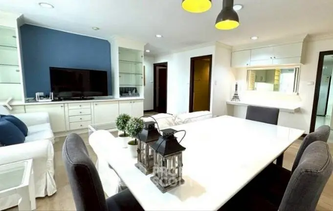 Spacious living room with modern decor and dining area, featuring elegant lighting and a cozy ambiance.