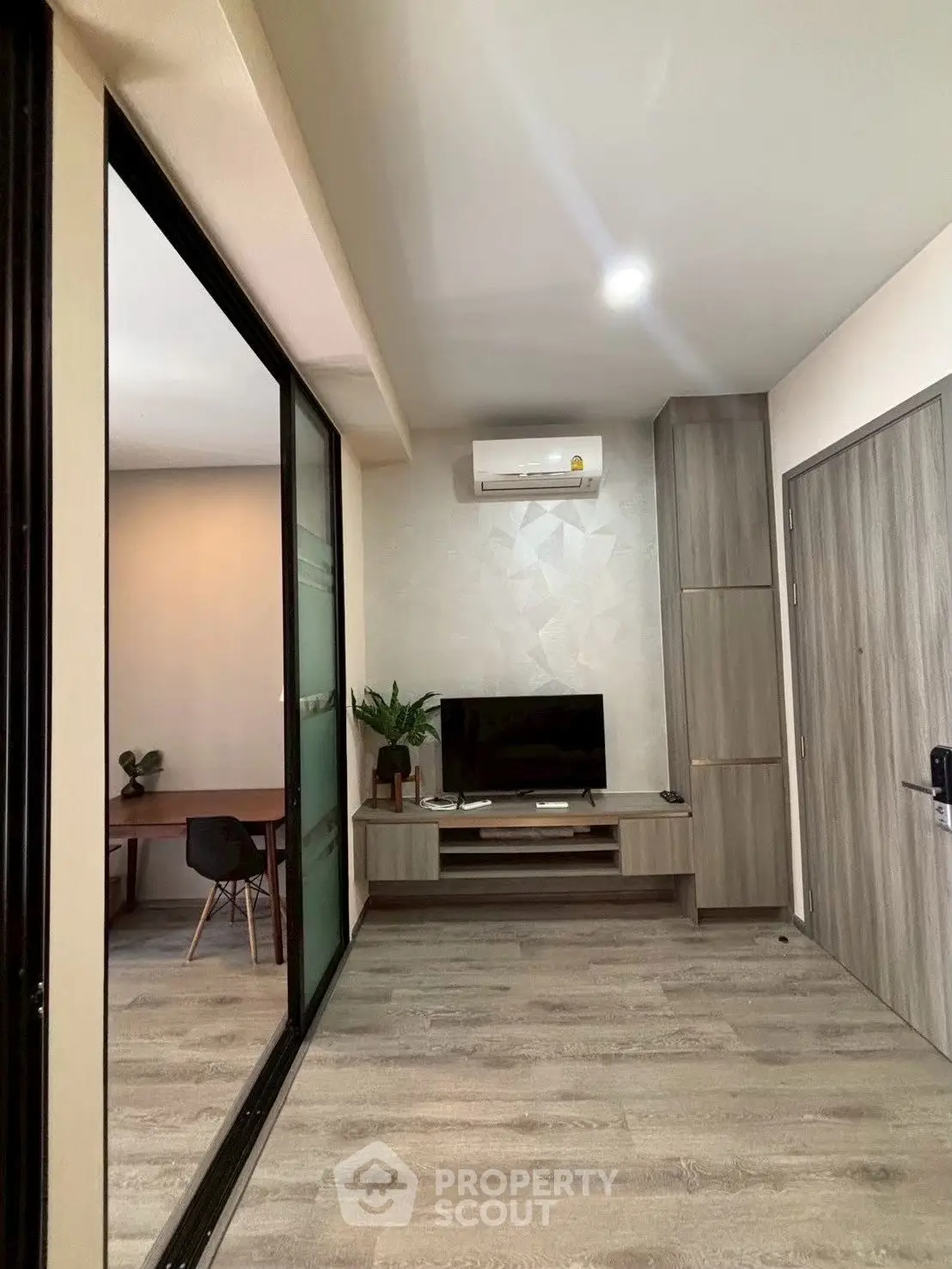 Modern living room with sleek design, featuring a TV unit, air conditioning, and stylish flooring.