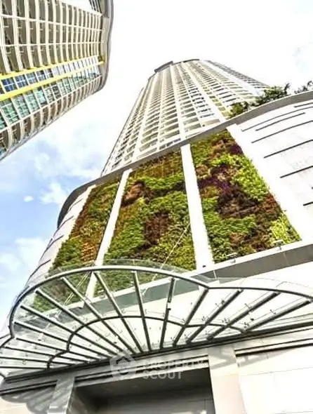 Stunning modern high-rise building with vertical garden and glass canopy entrance.