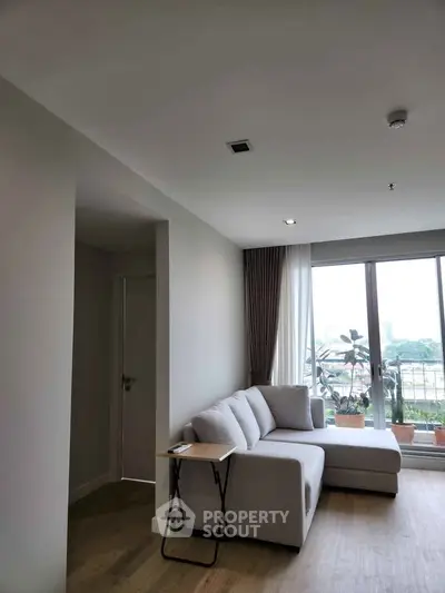 Modern living room with large windows and cozy sectional sofa, offering a bright and inviting atmosphere.