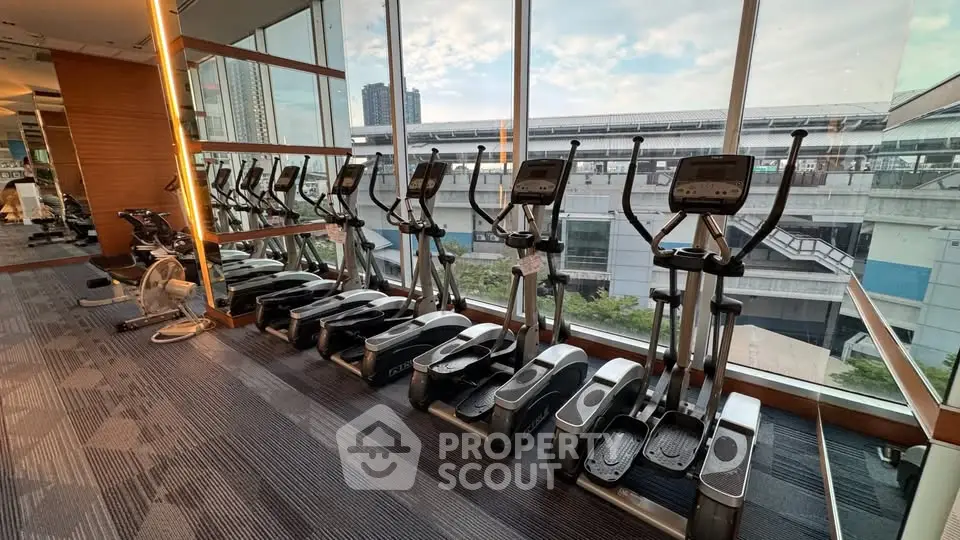 Modern gym with elliptical machines and city view through large windows