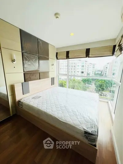 Modern bedroom with large windows and wooden flooring in a high-rise apartment.