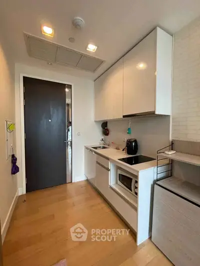 Modern compact kitchen with sleek cabinetry and integrated appliances in a stylish apartment.