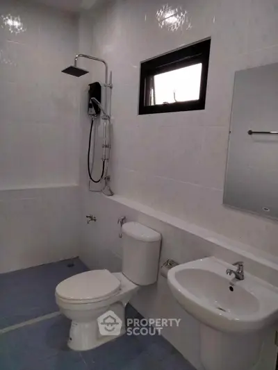 Modern bathroom with shower, toilet, and sink in a sleek white tiled design.