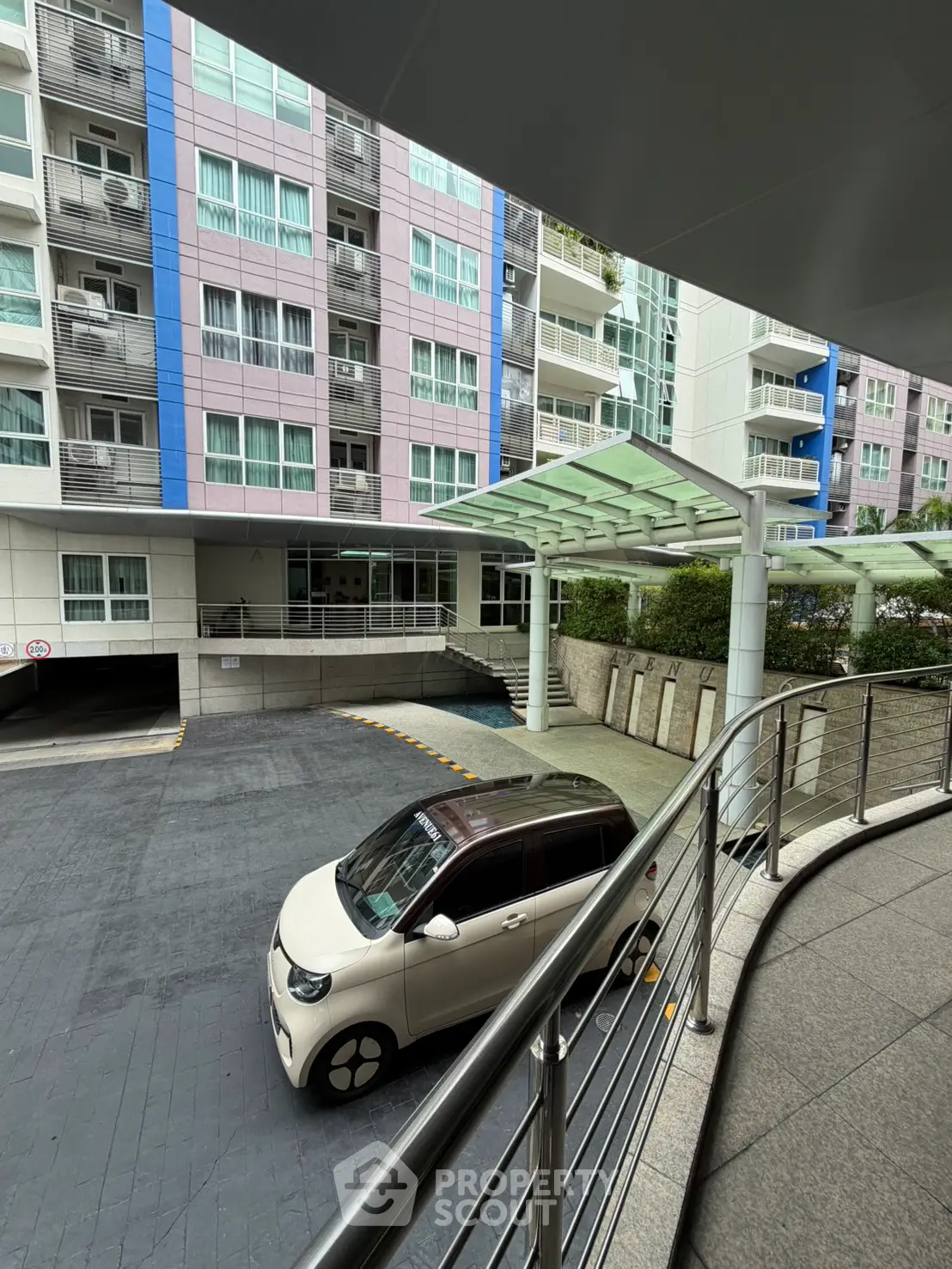 Modern apartment building exterior with parking area and sleek architectural design.