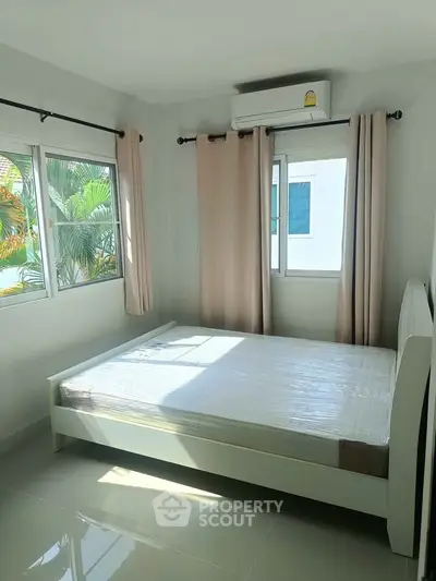 Bright bedroom with large windows and air conditioning unit, perfect for comfort and relaxation.