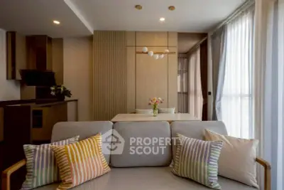 Modern living room with stylish decor and open kitchen layout, featuring cozy seating and elegant lighting.