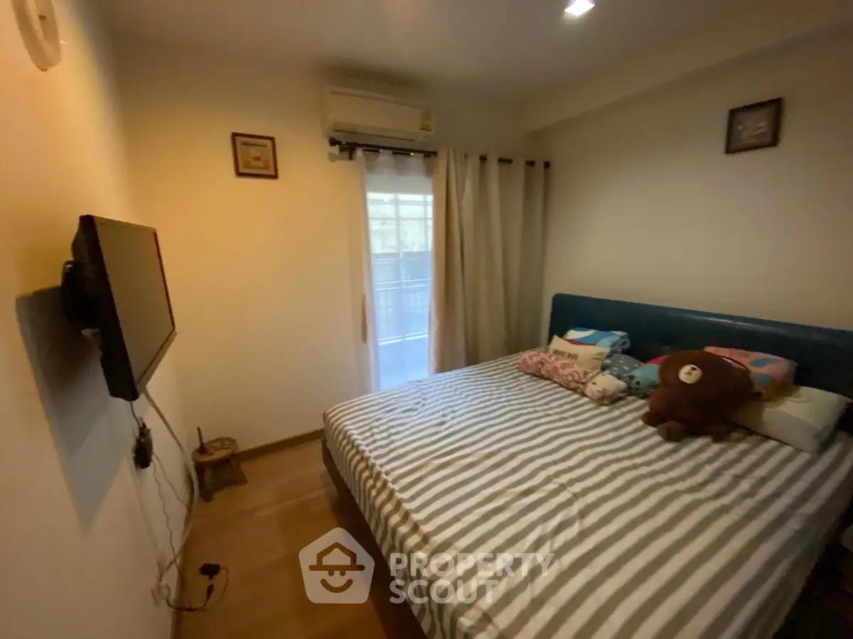 Cozy bedroom with striped bedding and wall-mounted TV, perfect for relaxation.