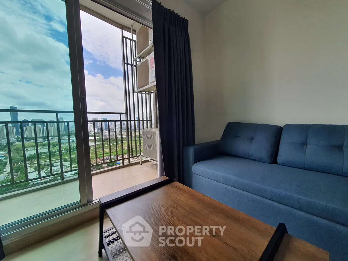Modern living room with blue sofa and balcony view of city skyline.