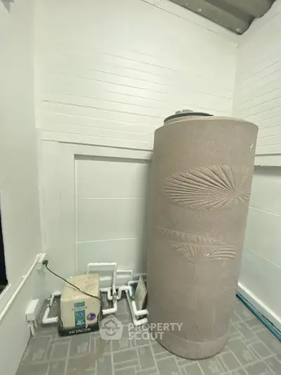 Spacious utility area with water tank and Hitachi pump, ideal for efficient home water management.