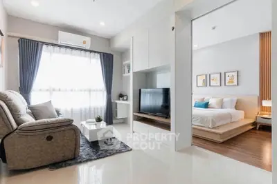 Modern open-plan living room with cozy seating and elegant bedroom view.