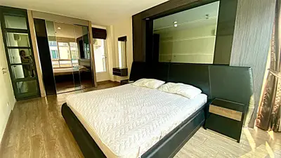 Spacious modern bedroom with large bed and mirrored wardrobe in luxury apartment