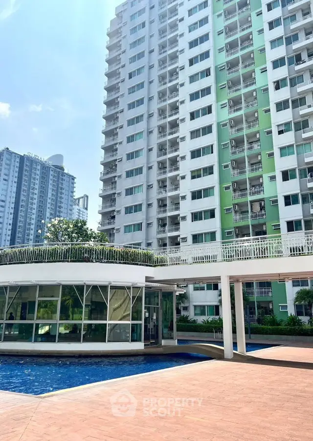Modern high-rise building with pool and lush greenery, perfect urban living.