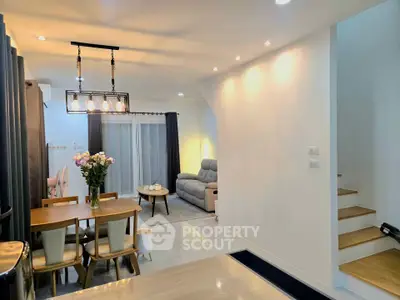 Modern open-plan living and dining area with stylish lighting and cozy seating.